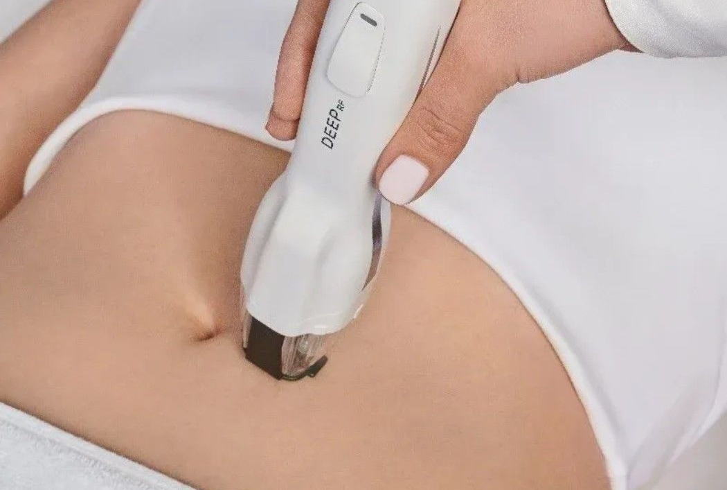 A woman in a white sweater is covering her face with her hands.