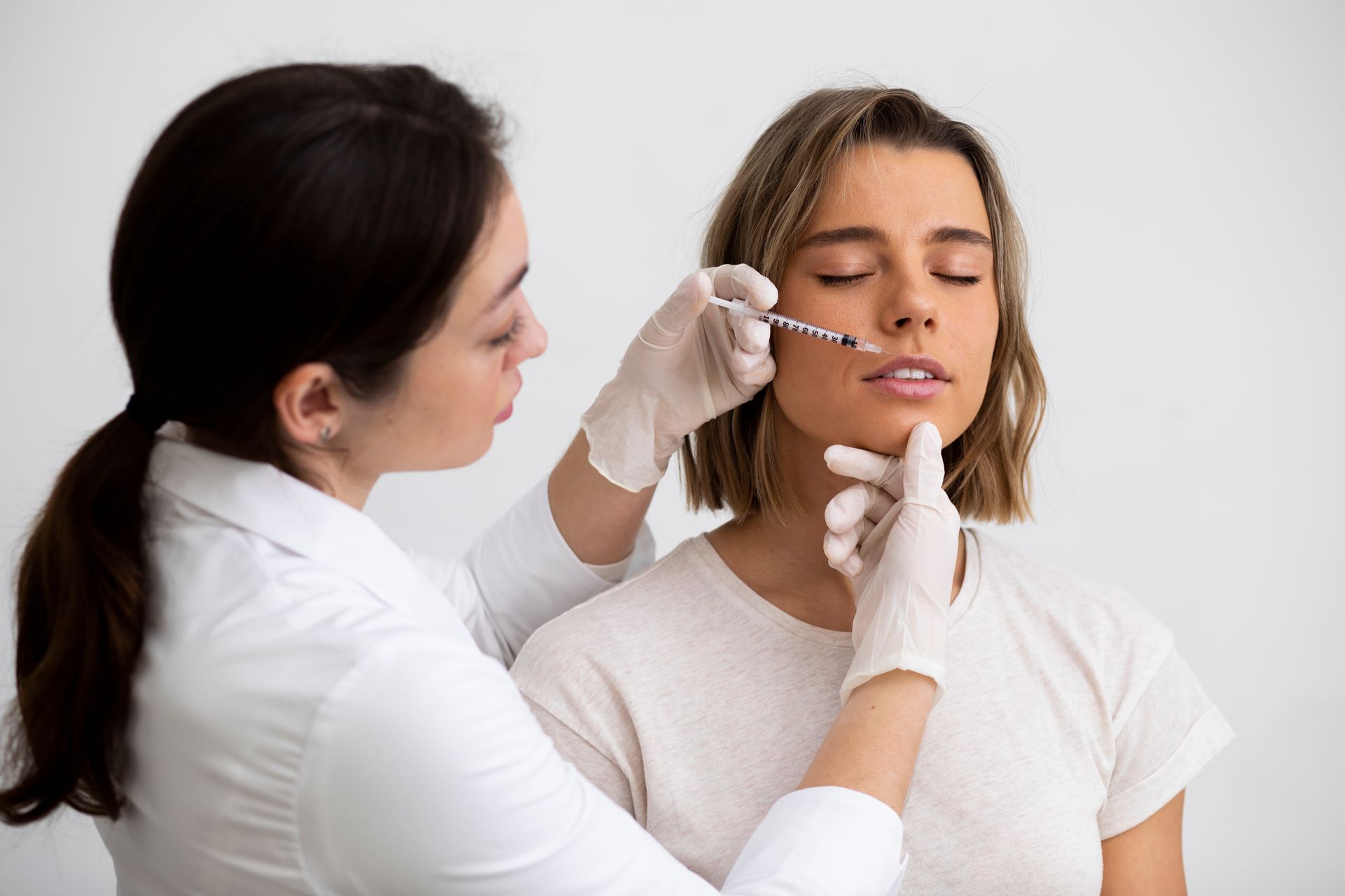 A woman is getting a botox injection in her lips.