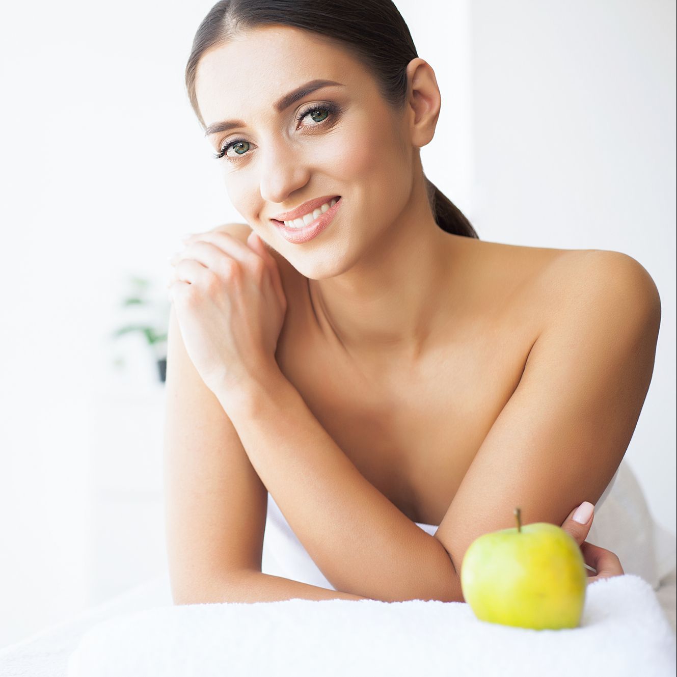 A woman is sitting on a towel next to an apple