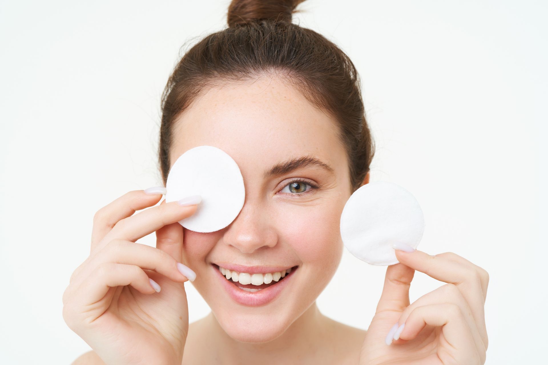 A woman is holding cotton pads in front of her eye.