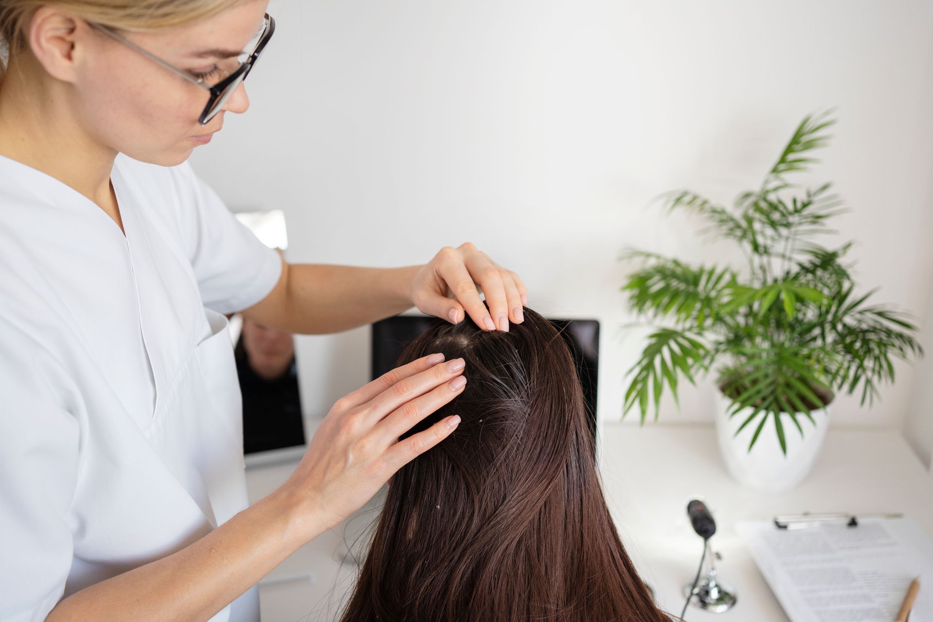 A woman is getting a hair treatment from a hairdresser.
