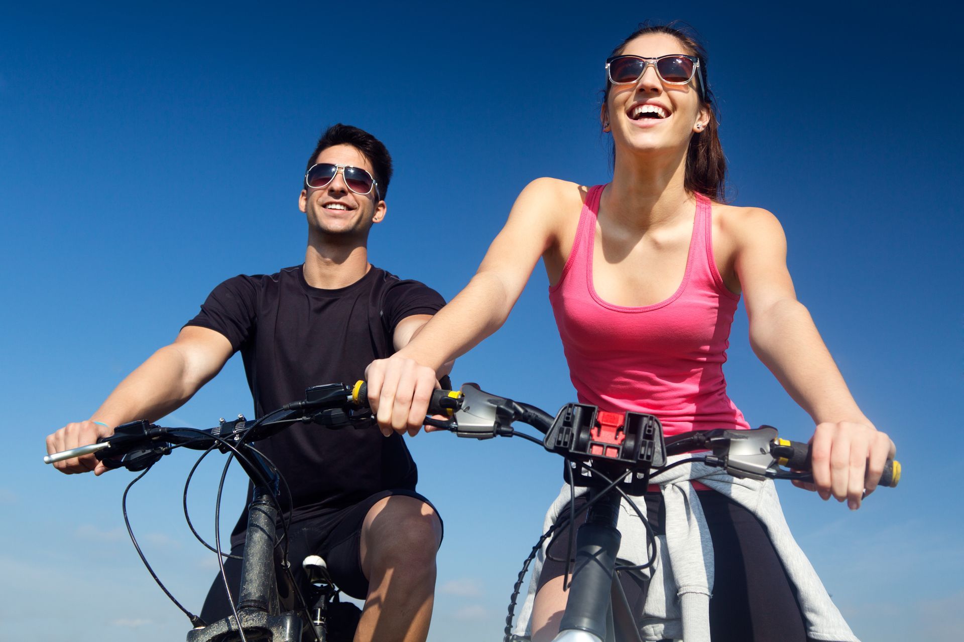 A man and a woman are riding bicycles on a sunny day.