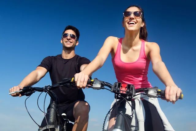 A man and a woman are riding bicycles on a sunny day.