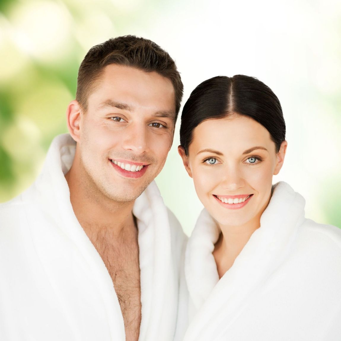 A man and a woman wearing bathrobes are smiling for the camera
