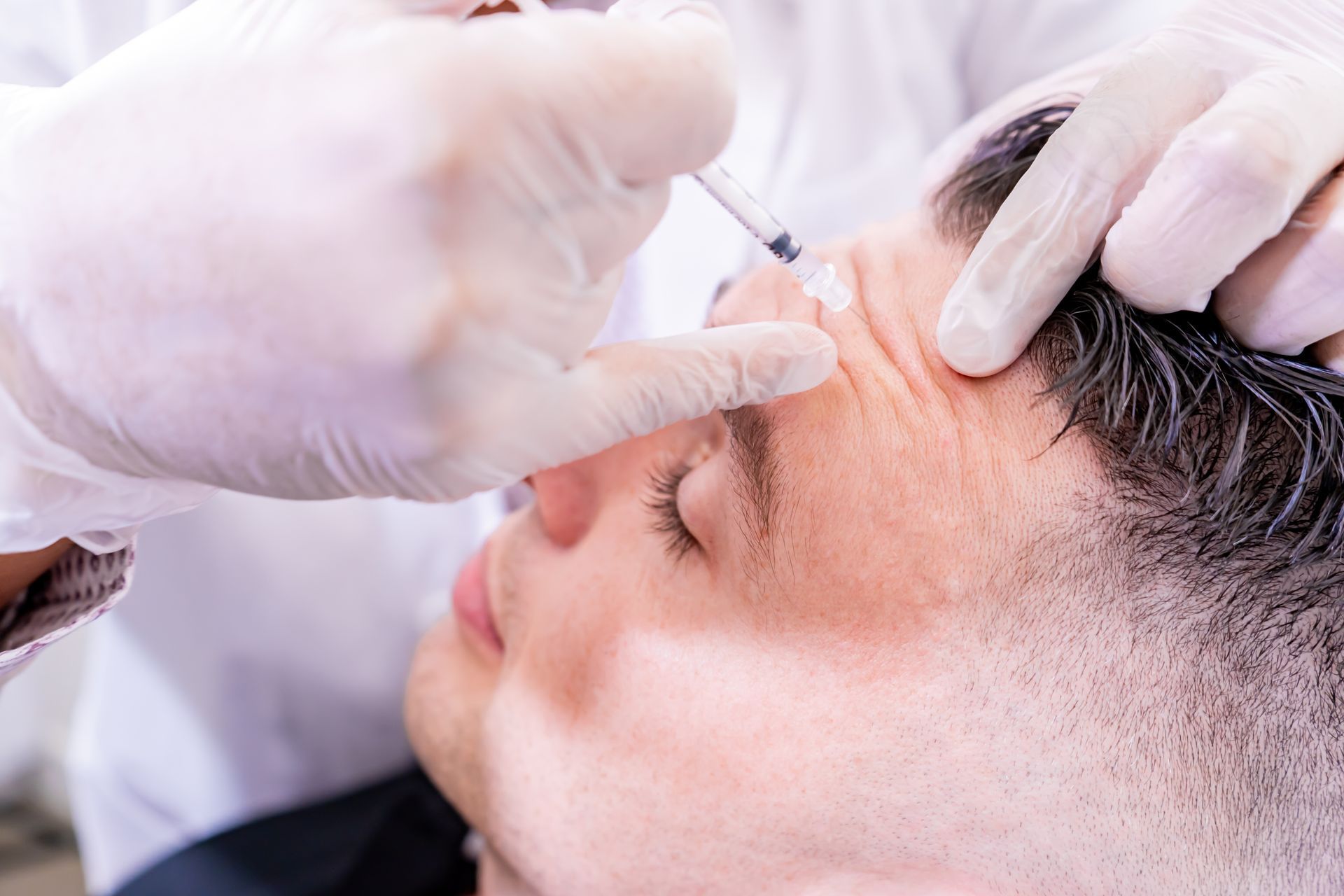 A man is getting a botox injection in his forehead.