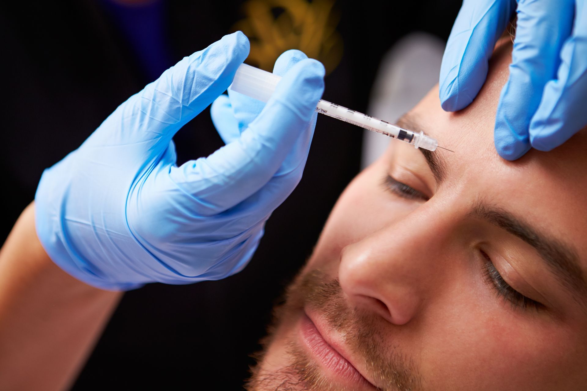 A man is getting a botox injection in his forehead.