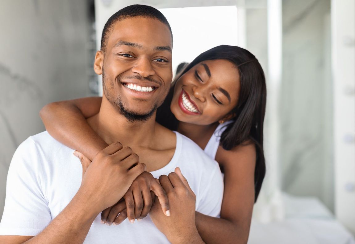 A man and a woman wearing bathrobes are smiling for the camera