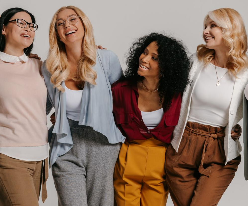 A woman in a white sweater is sitting in front of a window.
