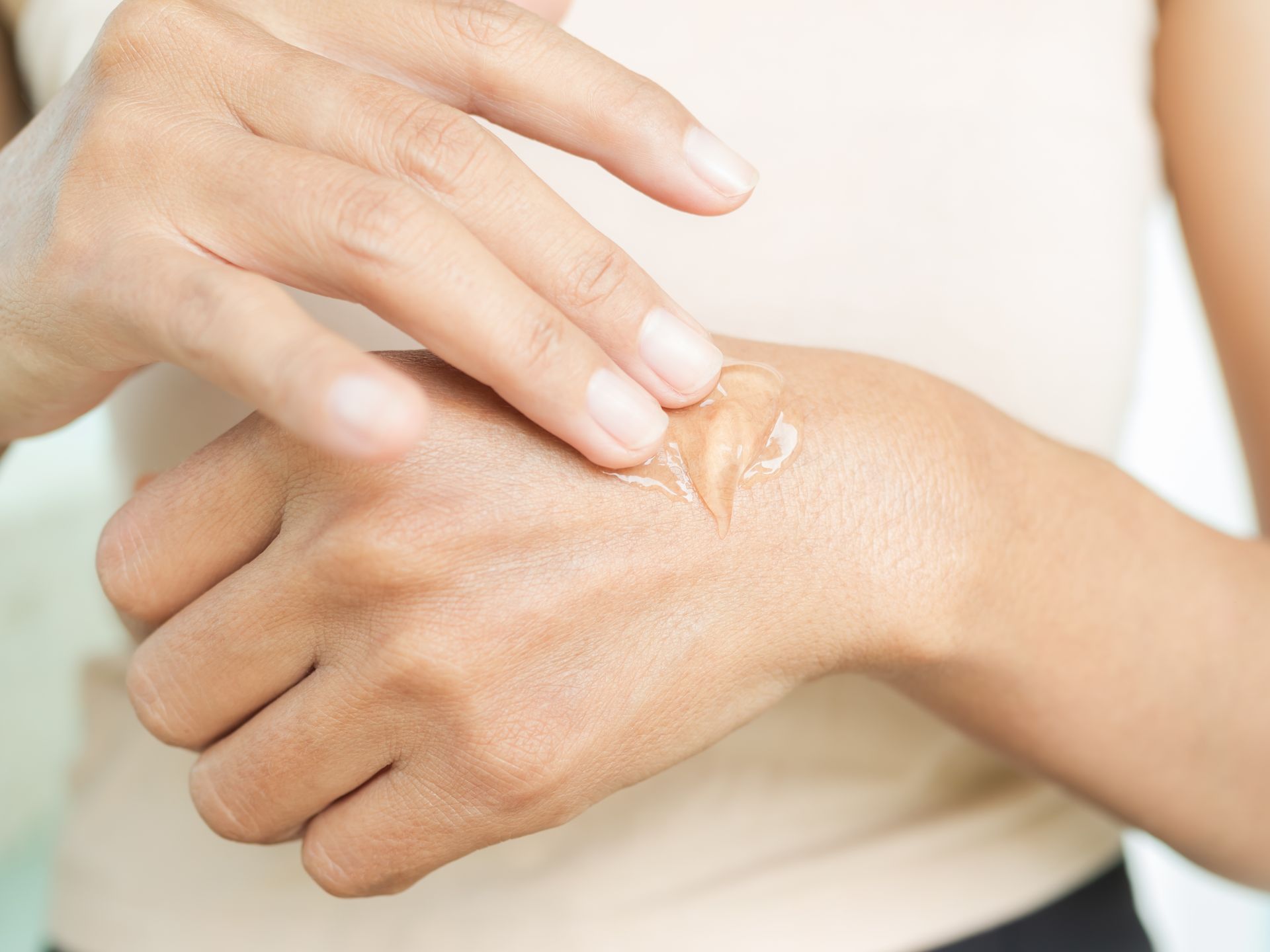 A woman is applying lotion to her hand.