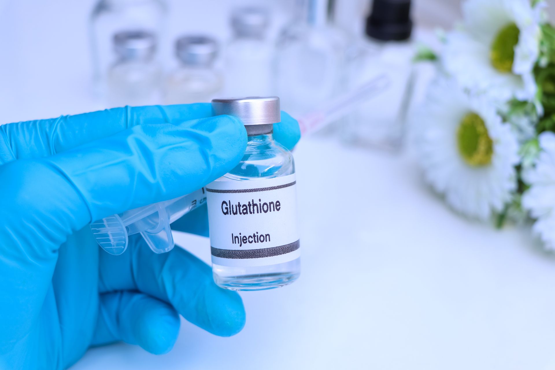 A person in a blue glove is holding a bottle of glutathione.