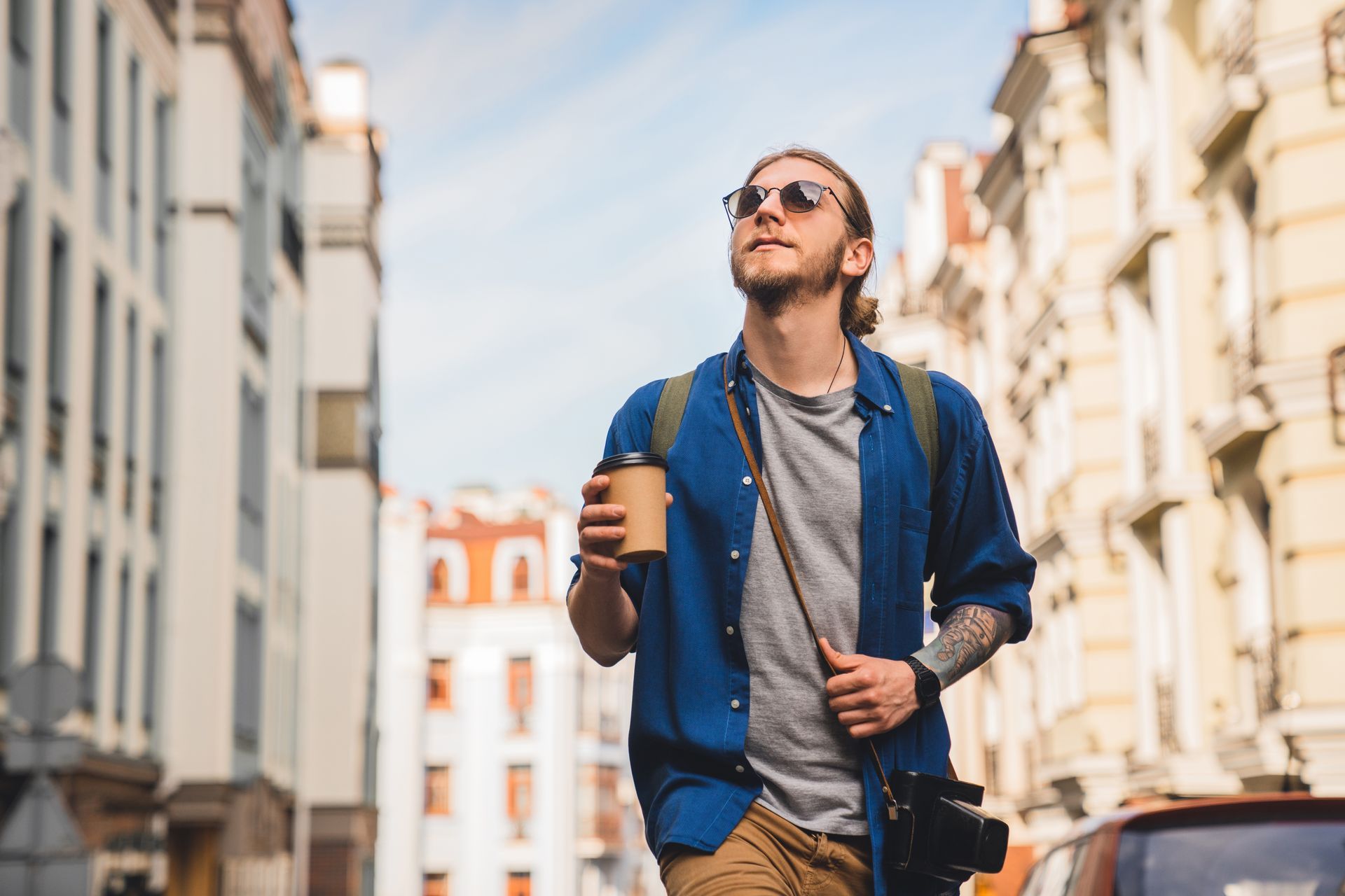A man is walking down a city street holding a cup of coffee.