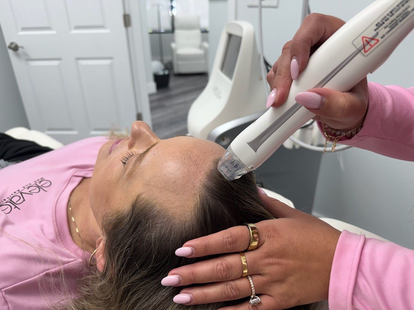 A woman is getting a hair treatment from a hairdresser.