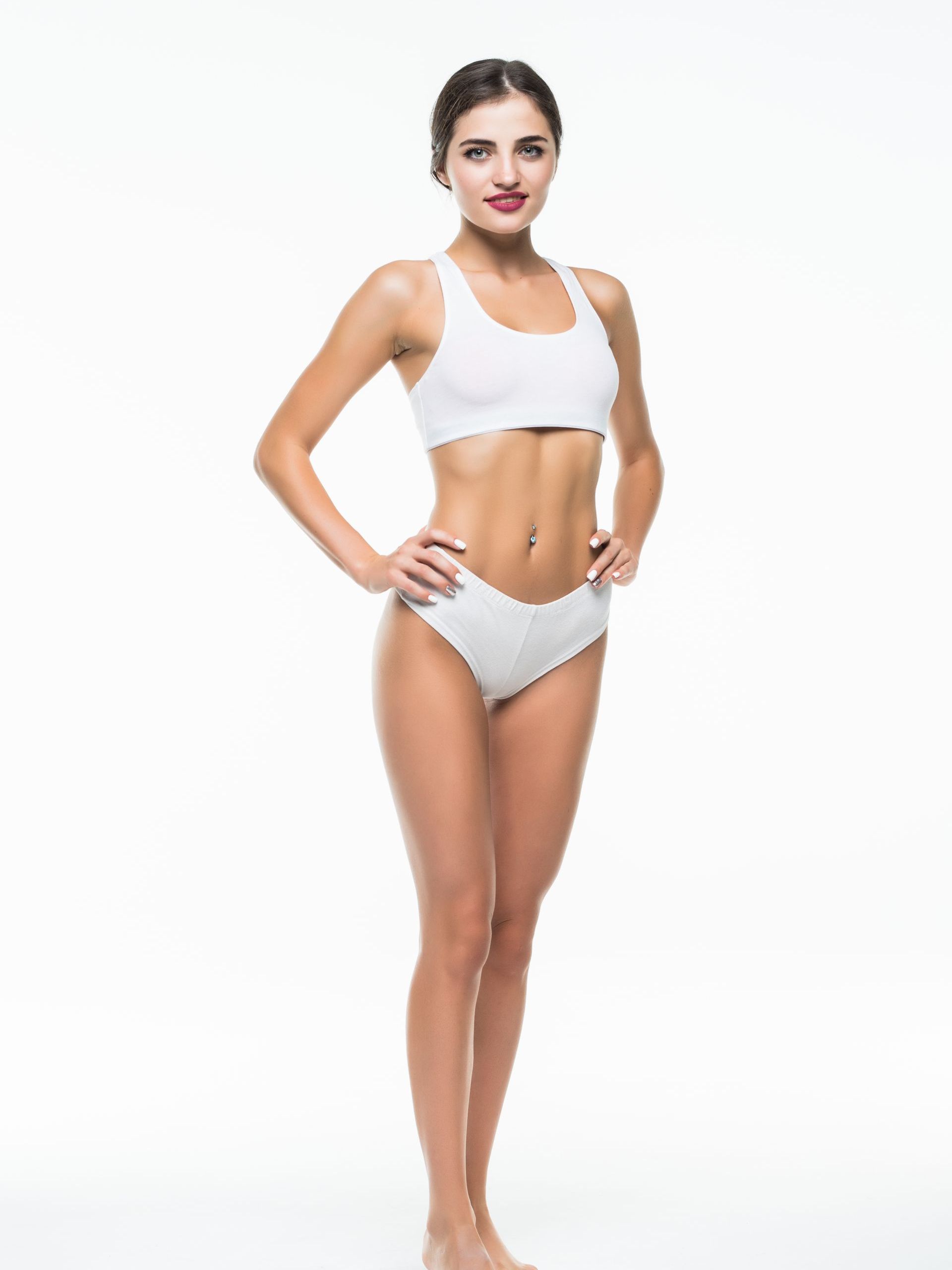 A woman in white underwear is standing with her hands on her hips on a white background.