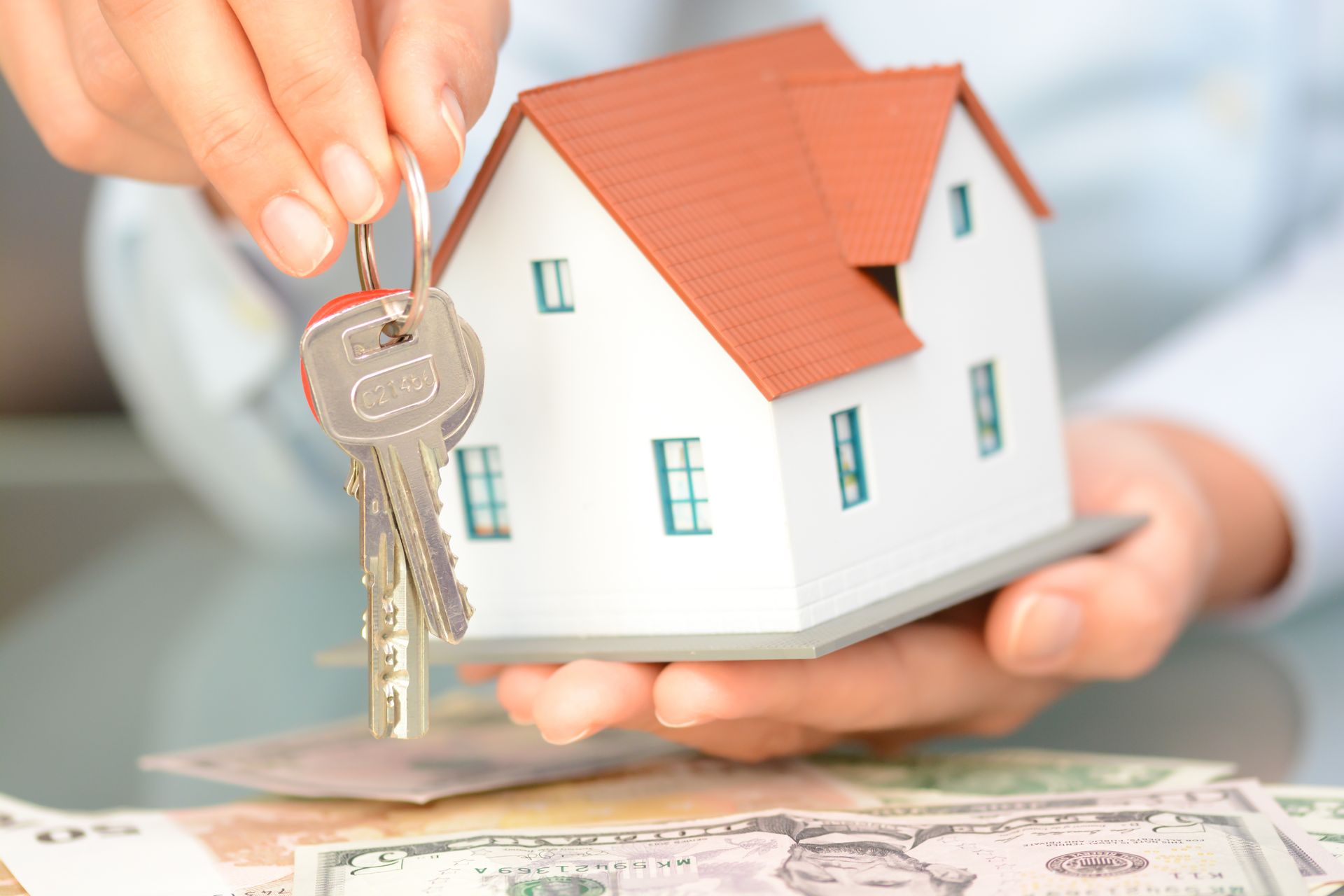 A person is holding a model house and keys in their hands.