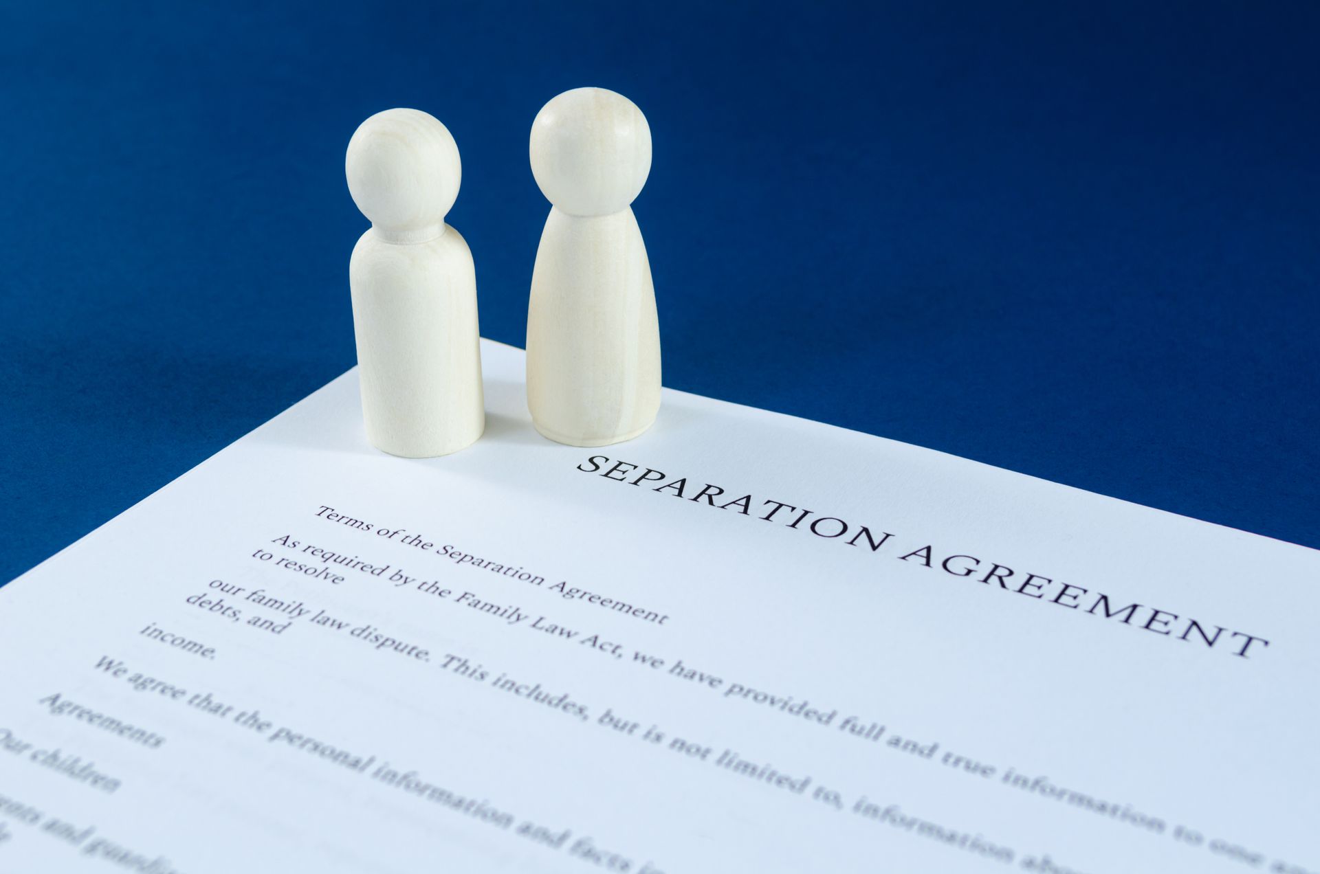 Two figurines are sitting on top of a separation agreement