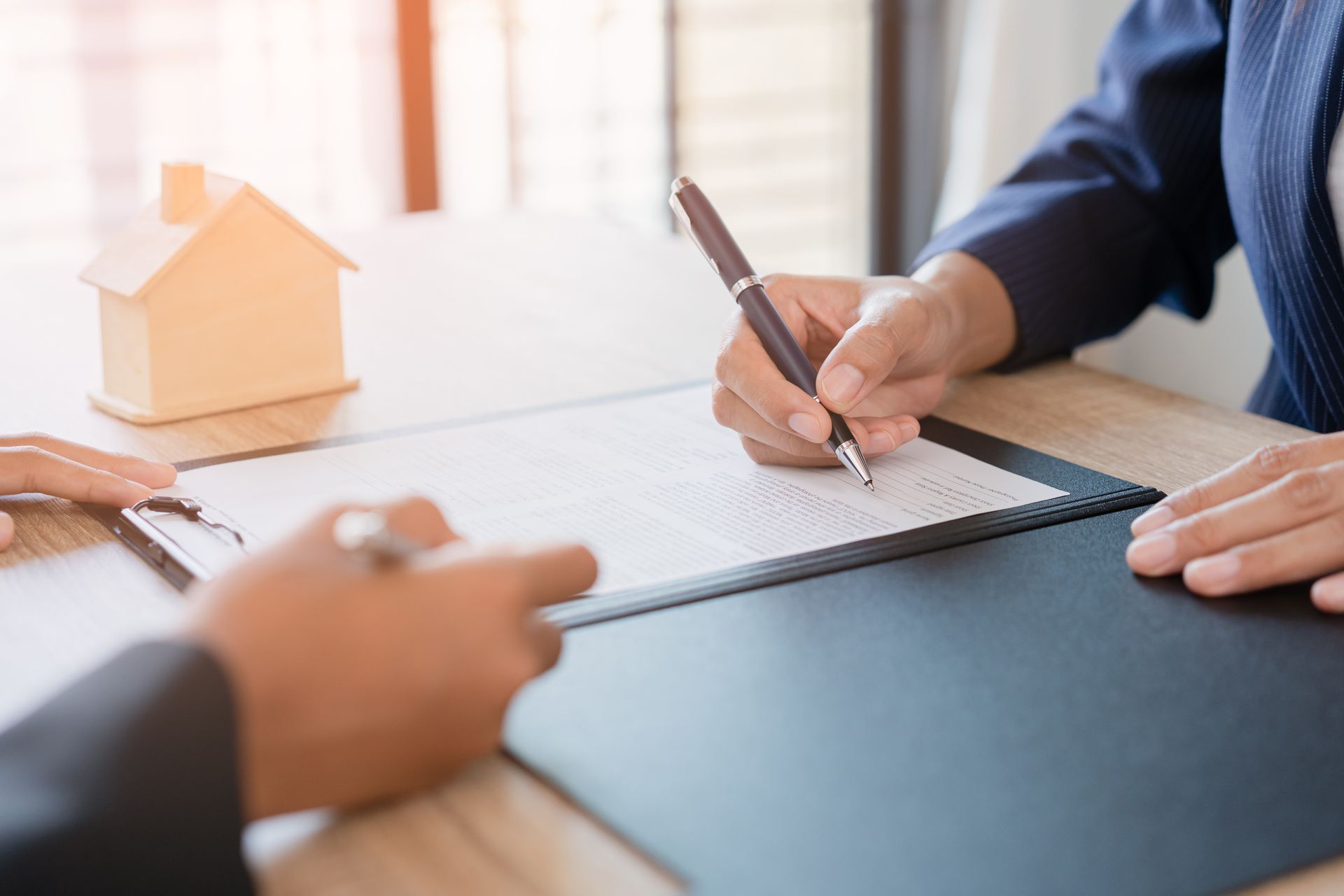 A person is signing a document with a pen on a clipboard.