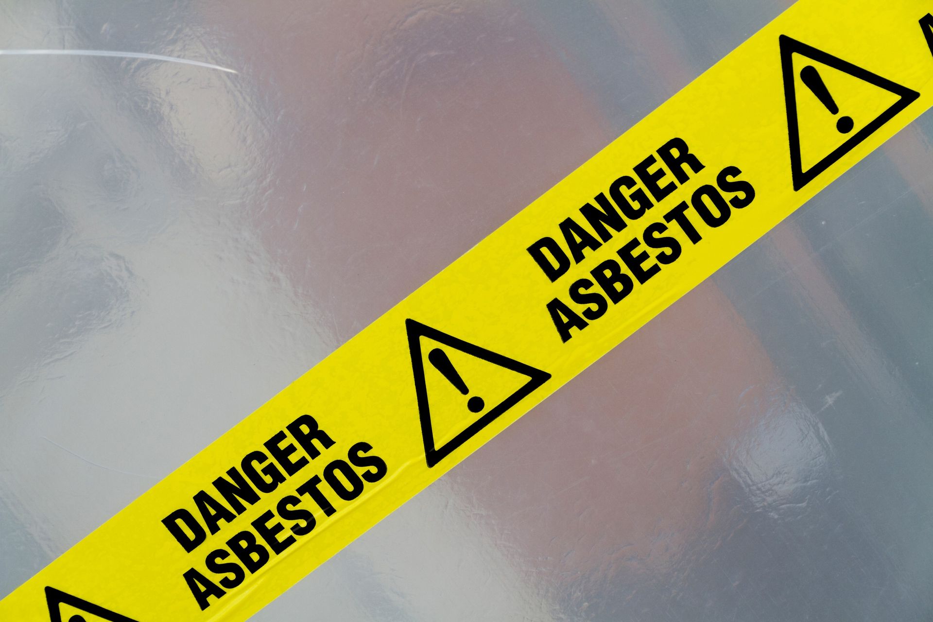 A yellow warning tape that says danger asbestos on it