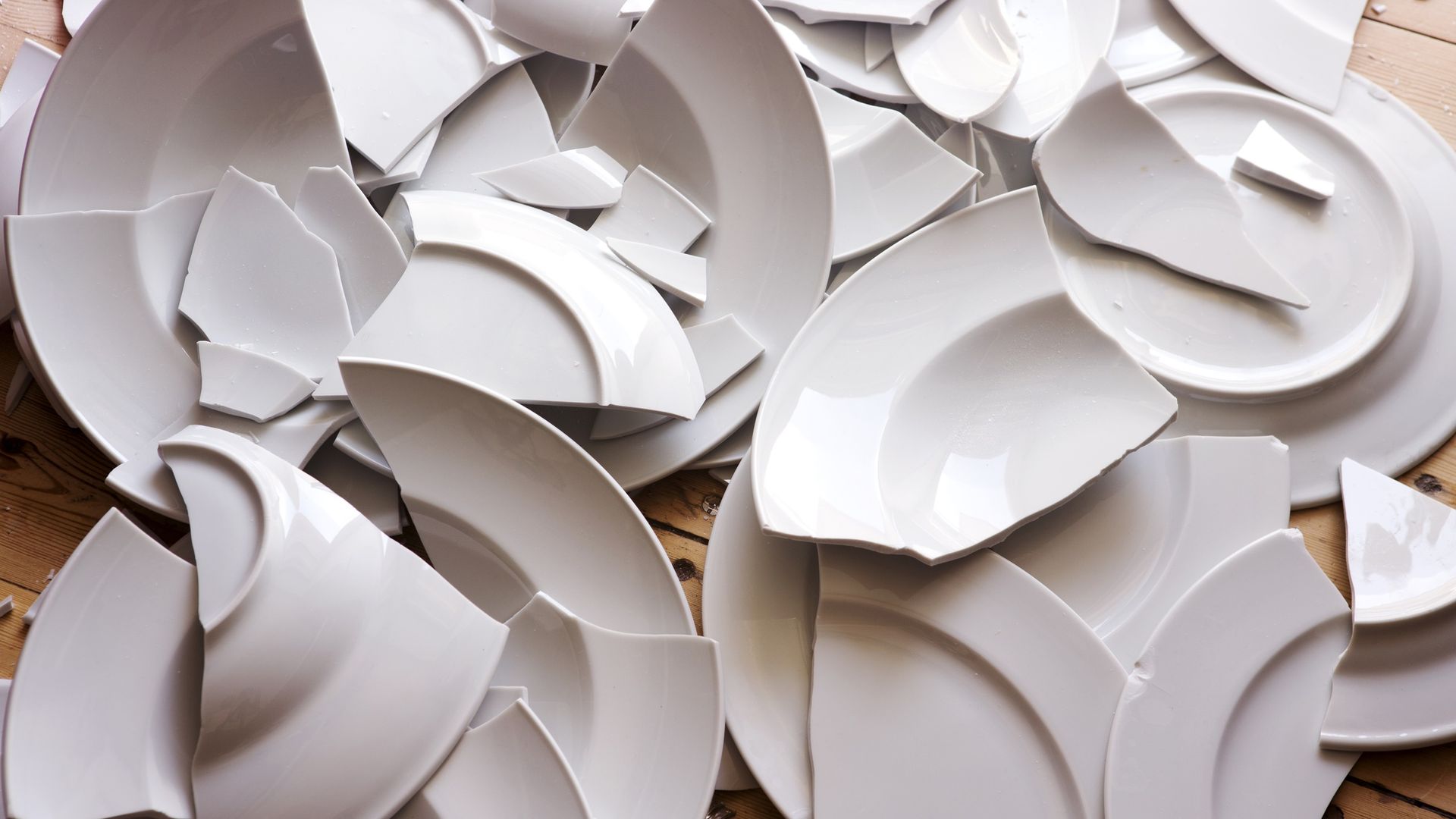 A pile of broken white plates on a wooden table