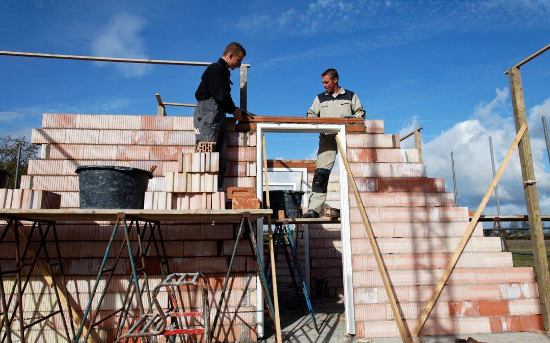 two construction workers are working on a brick wall