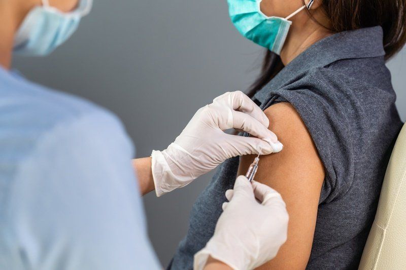 a woman wearing a mask is getting a vaccine in her arm