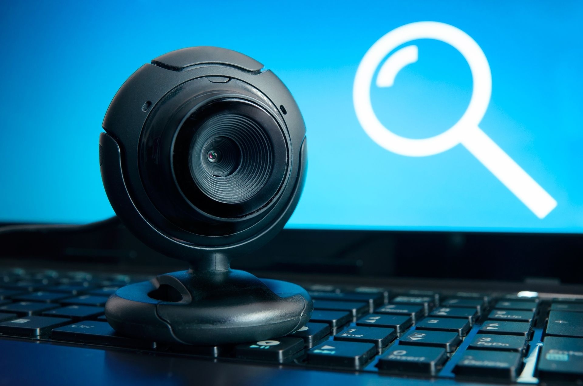 A webcam is sitting on top of a laptop keyboard