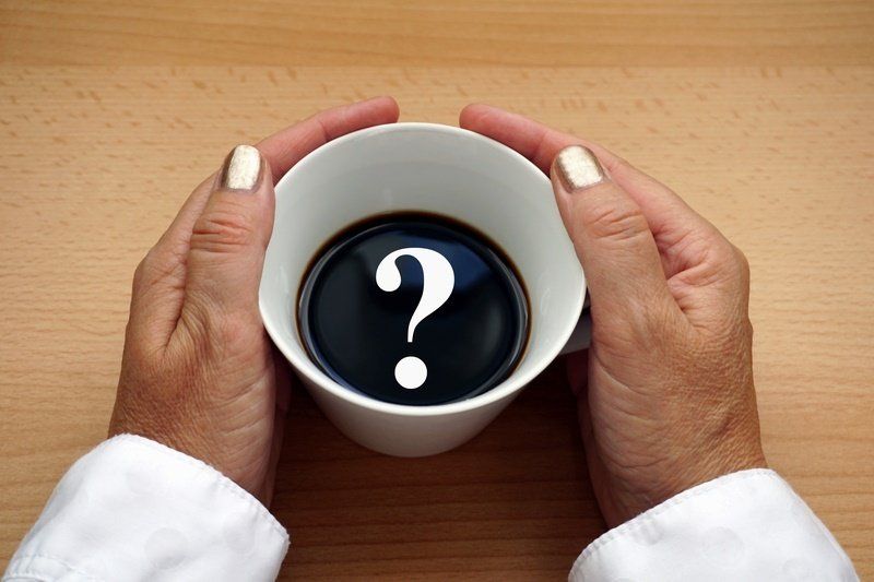 a person is holding a cup of coffee with a question mark on it
