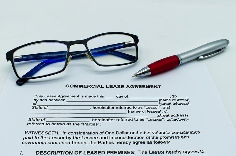 a pair of glasses and a pen are sitting on top of a commercial lease agreement