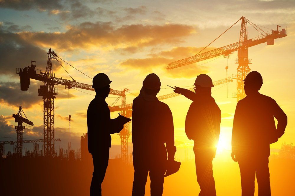 a group of construction workers are standing on a construction site at sunset