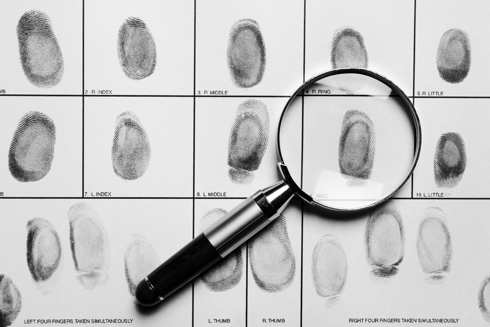 A magnifying glass is sitting on top of a collection of fingerprints