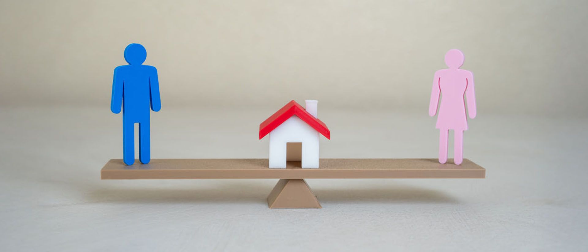 A seesaw with a blue person on one side, a house in the middle, and a pink person on the other side.