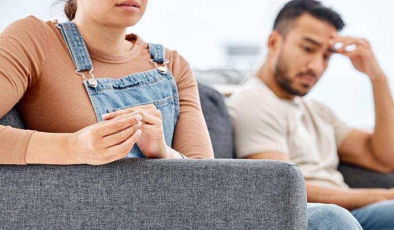 A man and a woman are sitting on a couch having an argument.