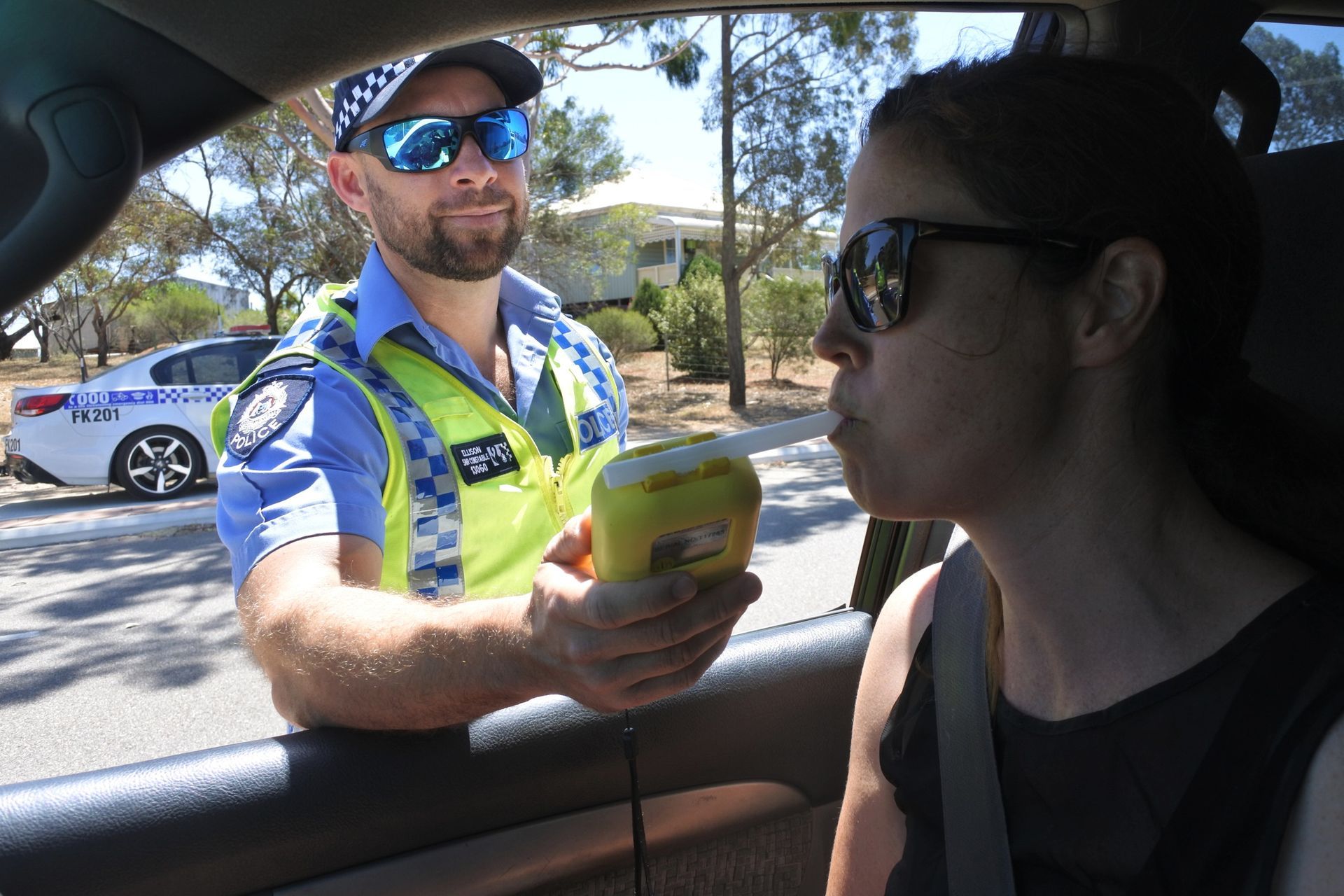 police holding a breathalyzer in front of a driver