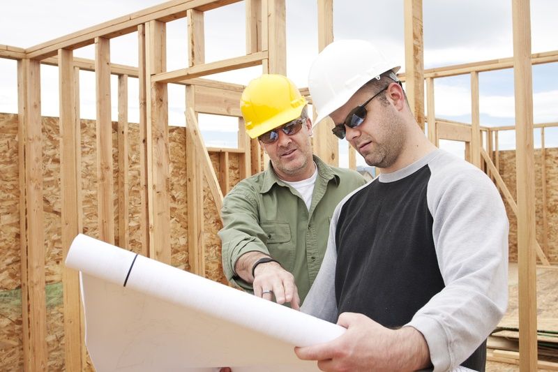 two construction workers are looking at a blueprint at a construction site