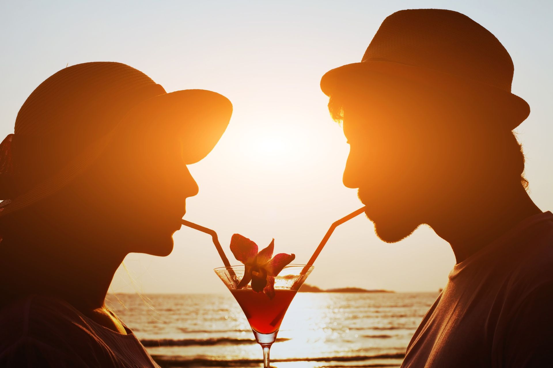 a man and a woman are drinking through straws from a martini glass