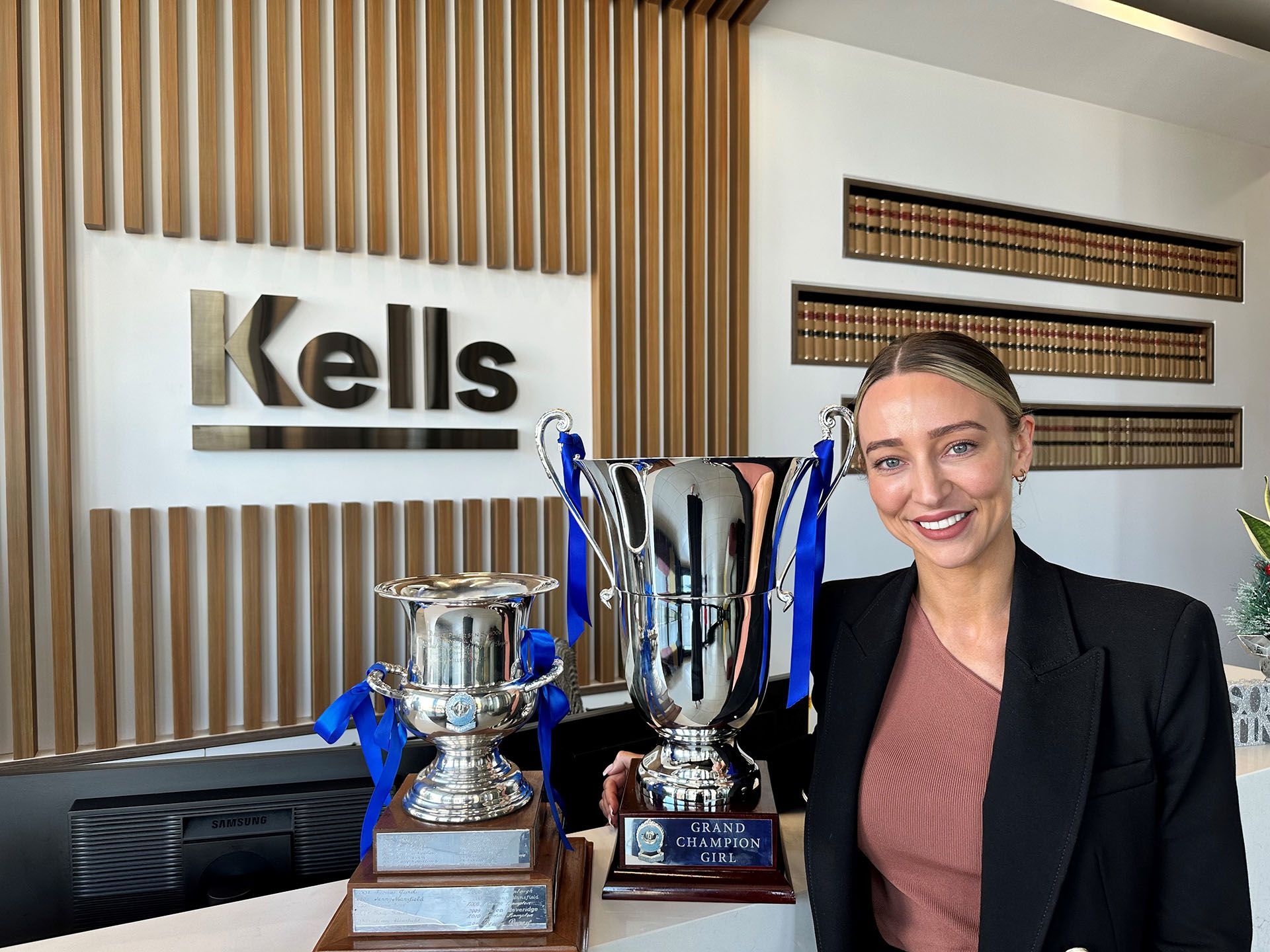 Ashleigh Barry holding two trophies in front of a Kells sign
