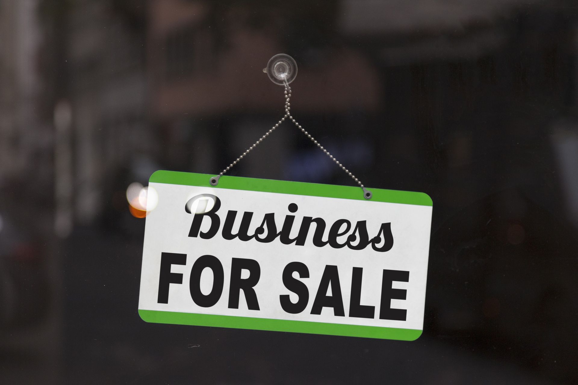 A business for sale sign hangs from a window
