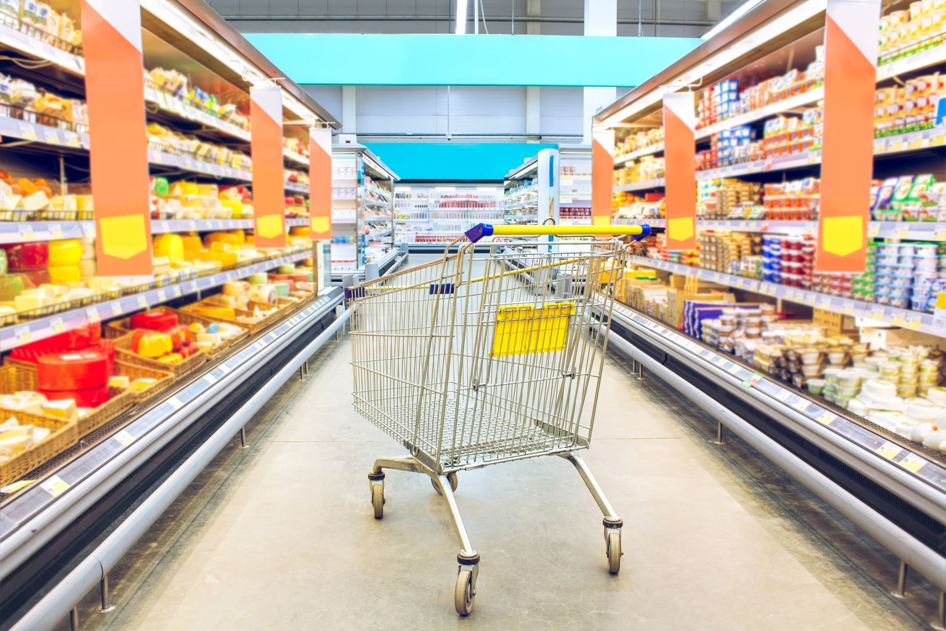 A shopping cart is sitting in the middle of an aisle in a supermarket.