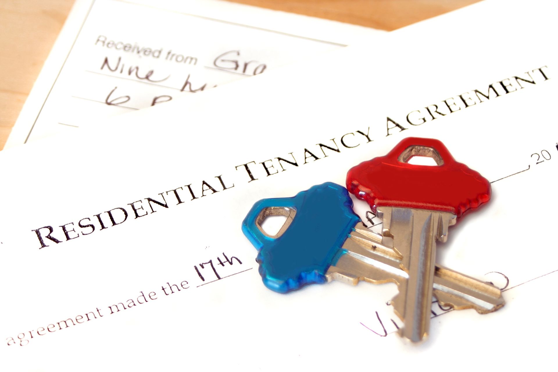 A bunch of keys on top of a residential tenancy agreement