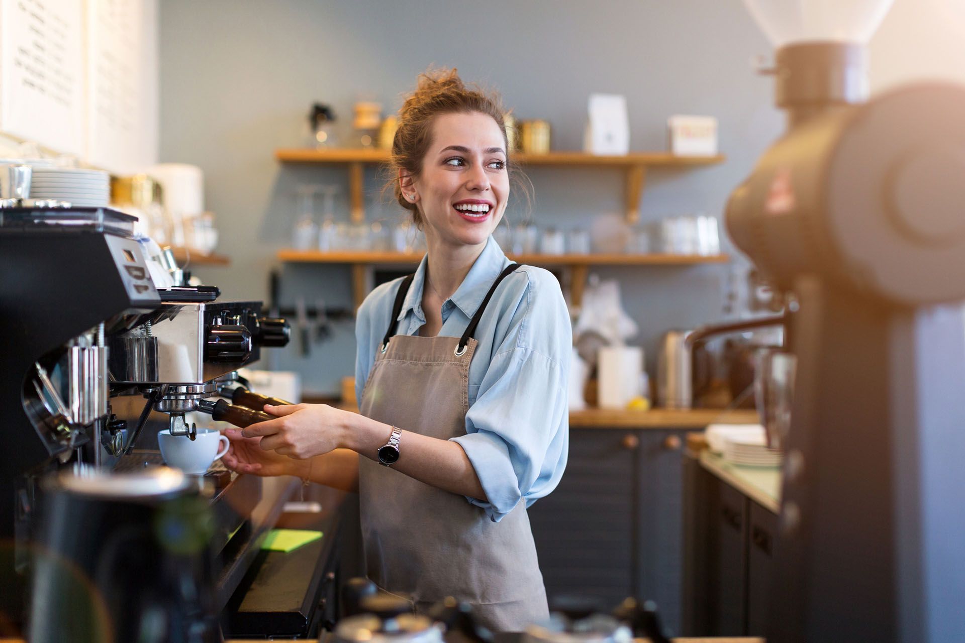 A woman is making coffee in a coffee shop.