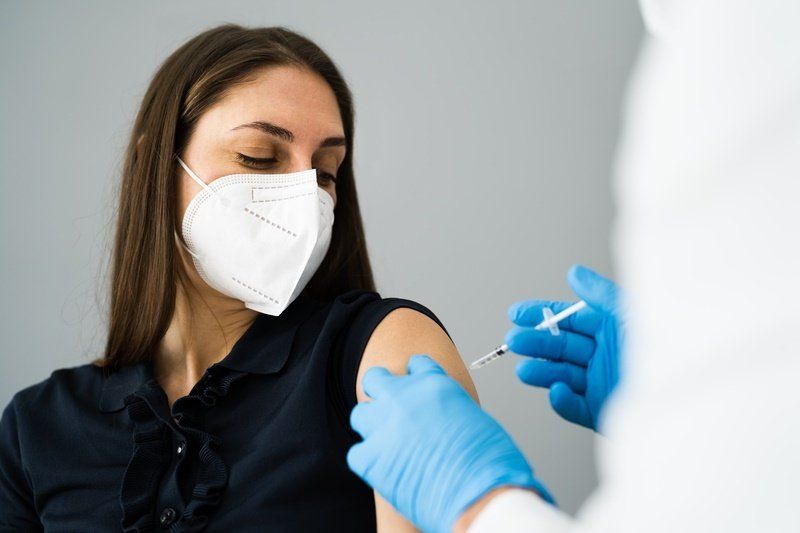 a woman wearing a mask is getting a vaccine from a doctor
