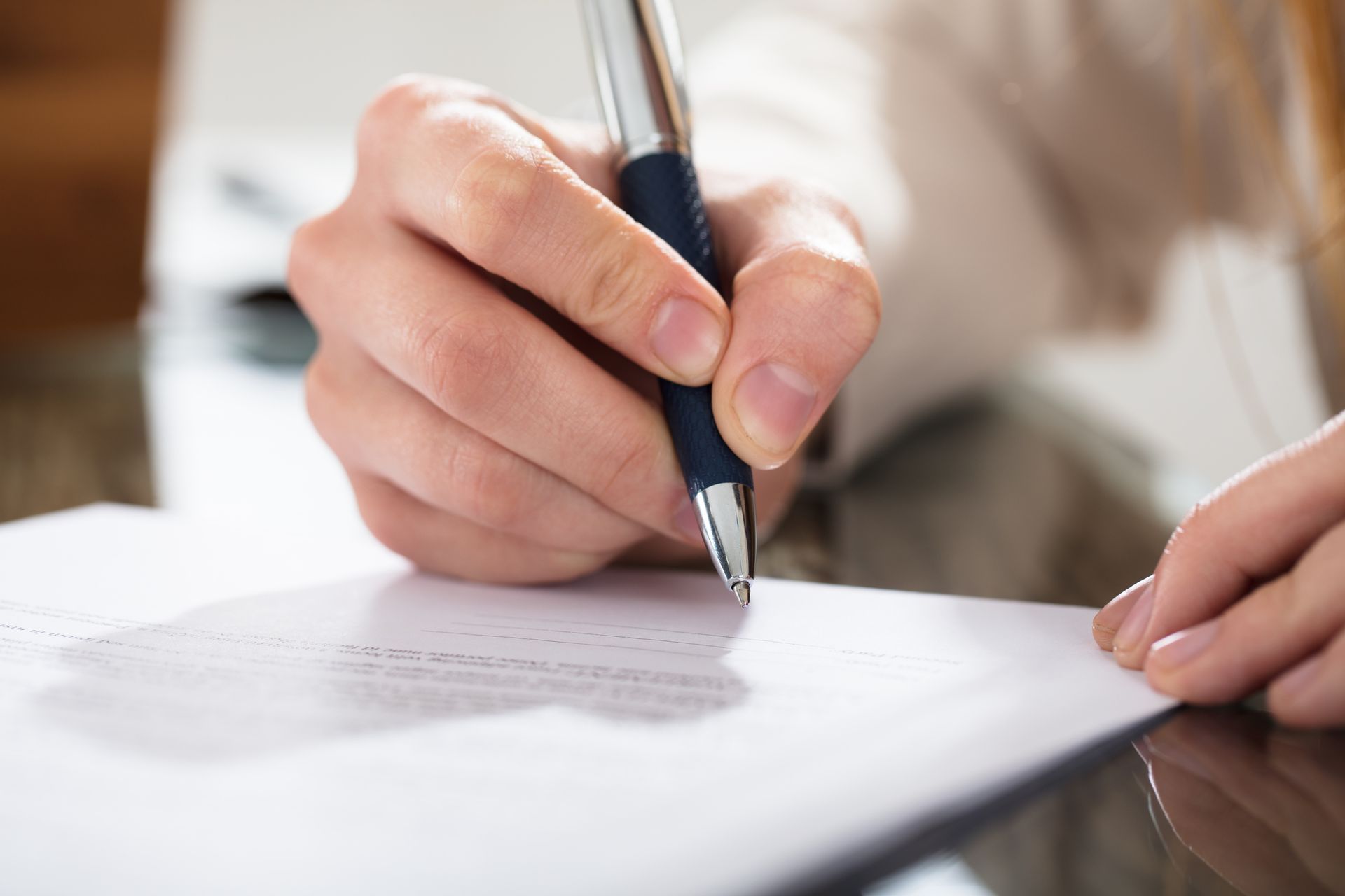 A person is writing on a piece of paper with a pen.
