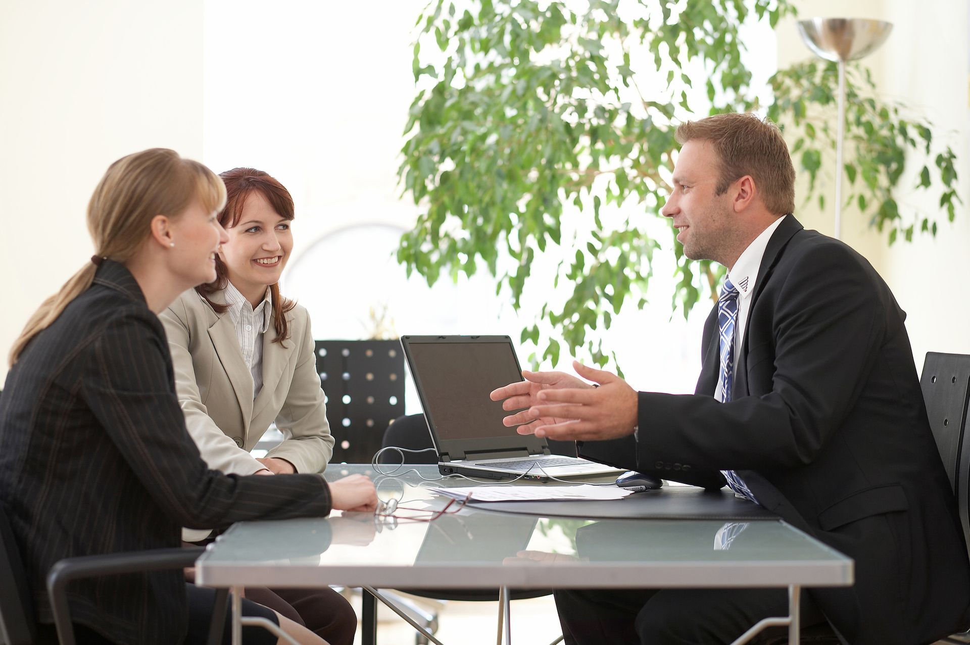 A man and two women are sitting at a table talking to each other