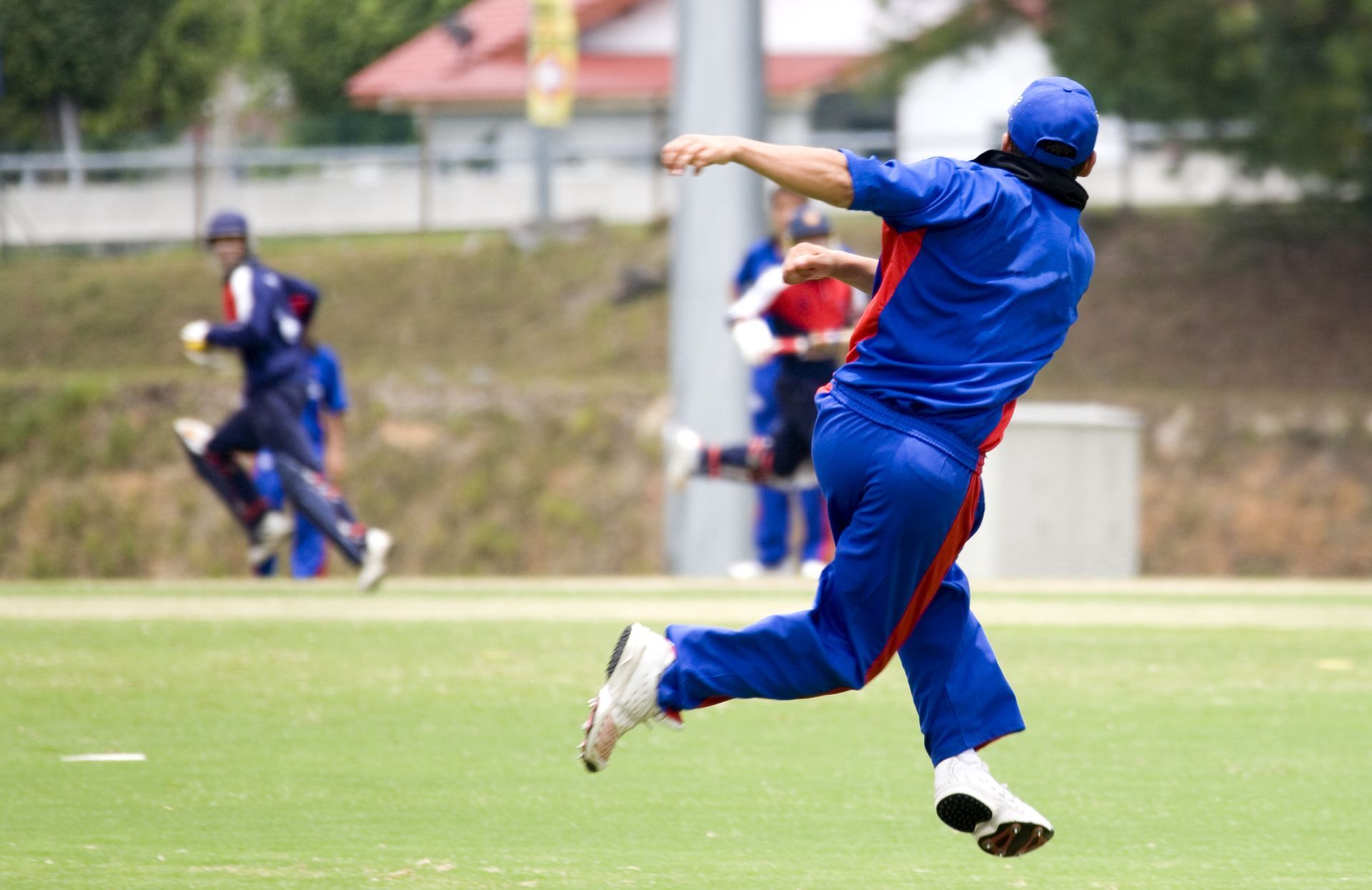 A man in a blue uniform is throwing a ball on a field.