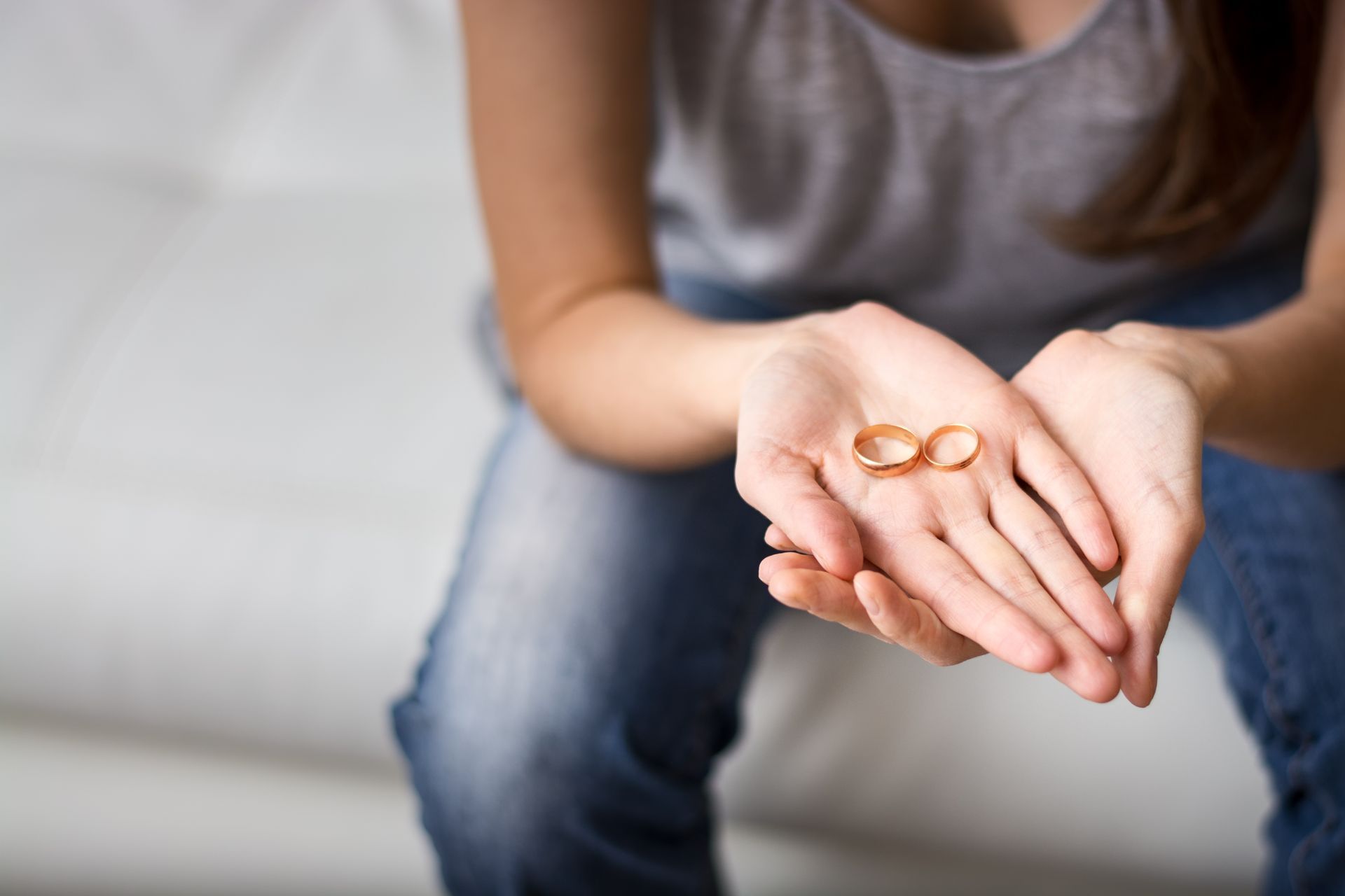 A woman is holding two wedding rings in her hands.