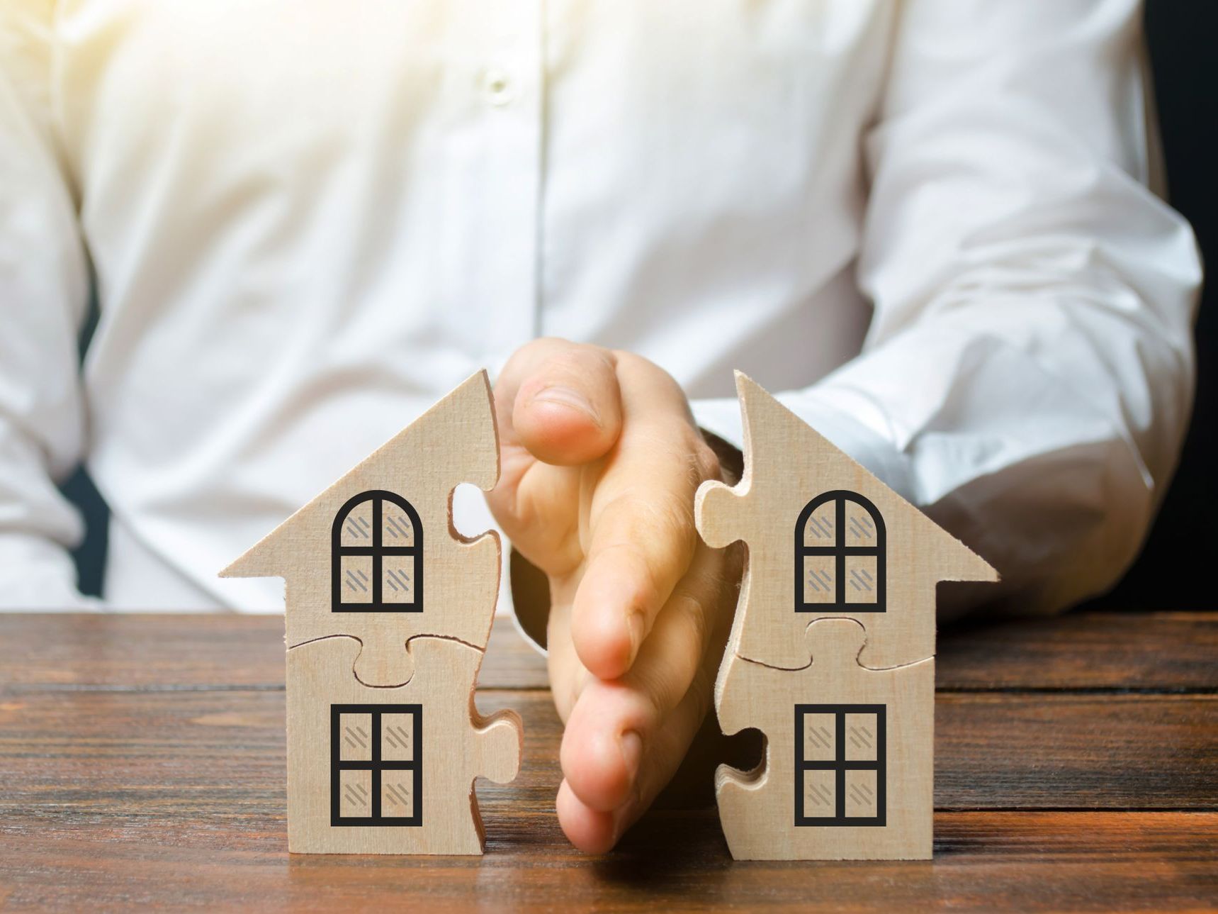 A man is holding two wooden houses in his hands.