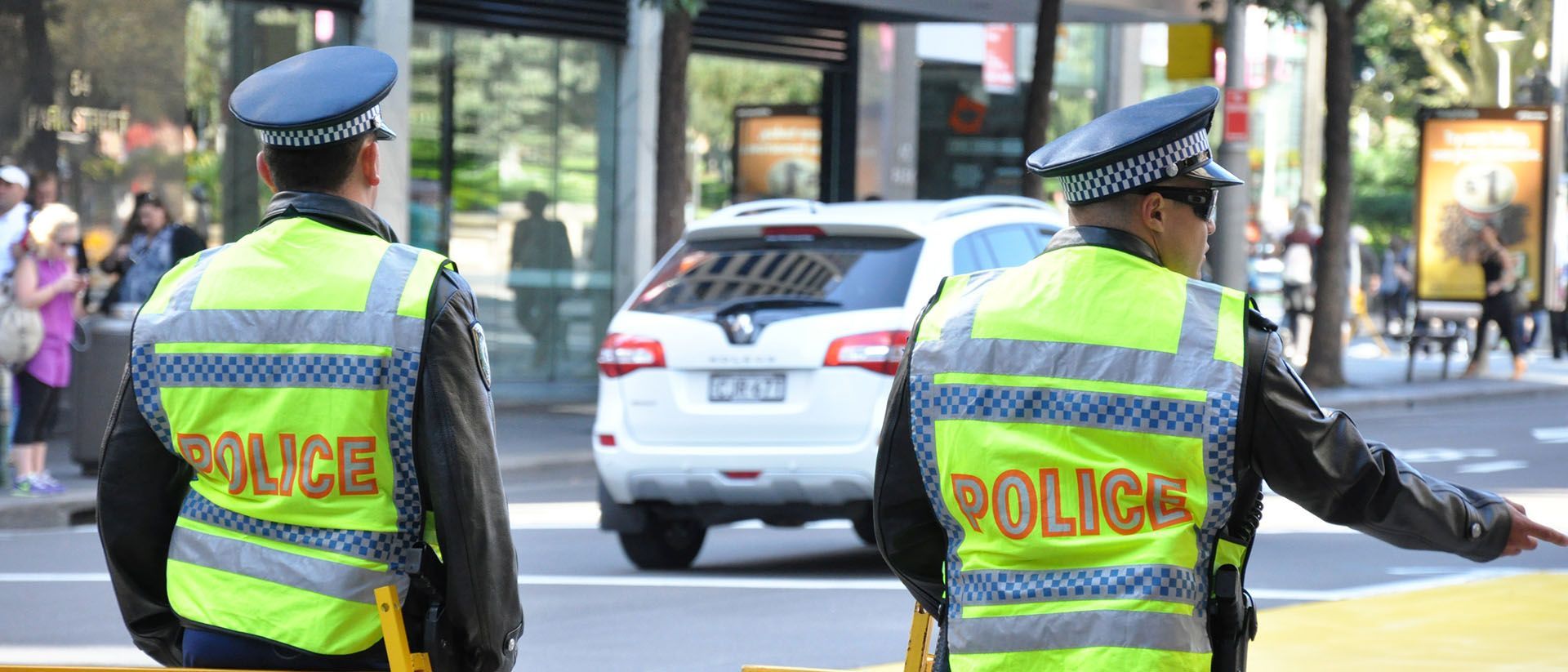 Two police officers are standing next to each other on the side of the road