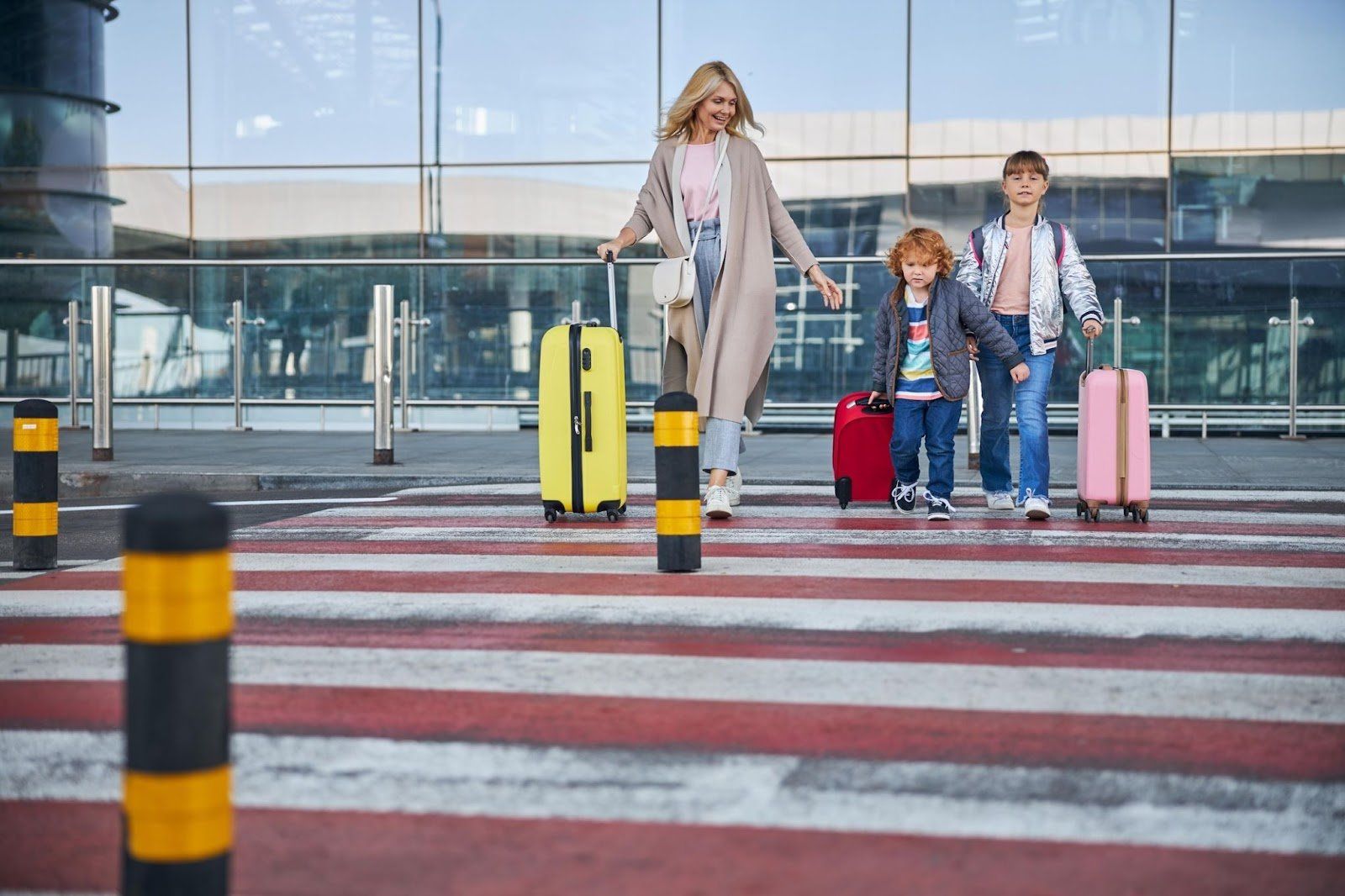 a woman and two children are walking with luggage at an airport .