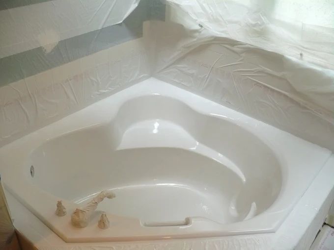 Modern bathroom with a white freestanding tub, woven rug, and tall windowed door.