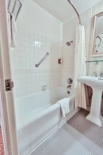Modern bathroom with glass shower, freestanding tub, and bedroom visible through open doorway