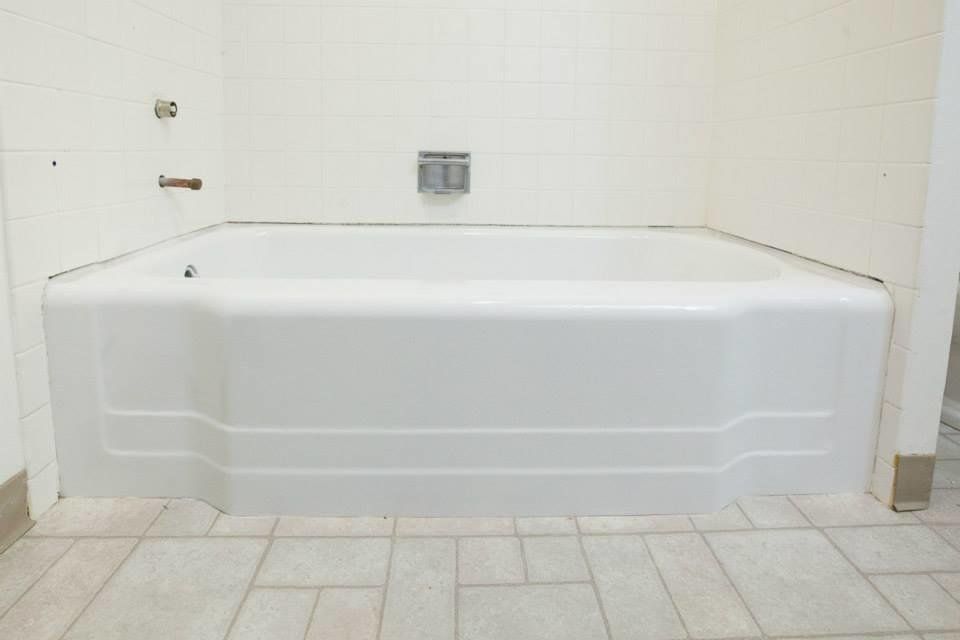 White bathtub in a tiled bathroom with grab bars and a wall-mounted faucet